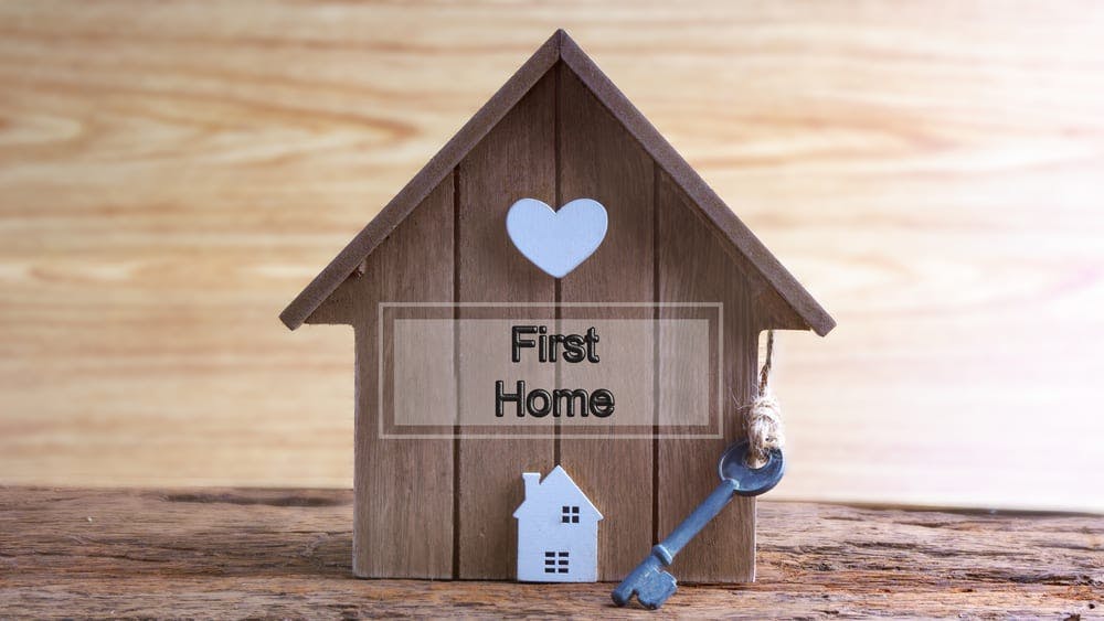 a wooden mini house box with a key hanging with a sign says First Home