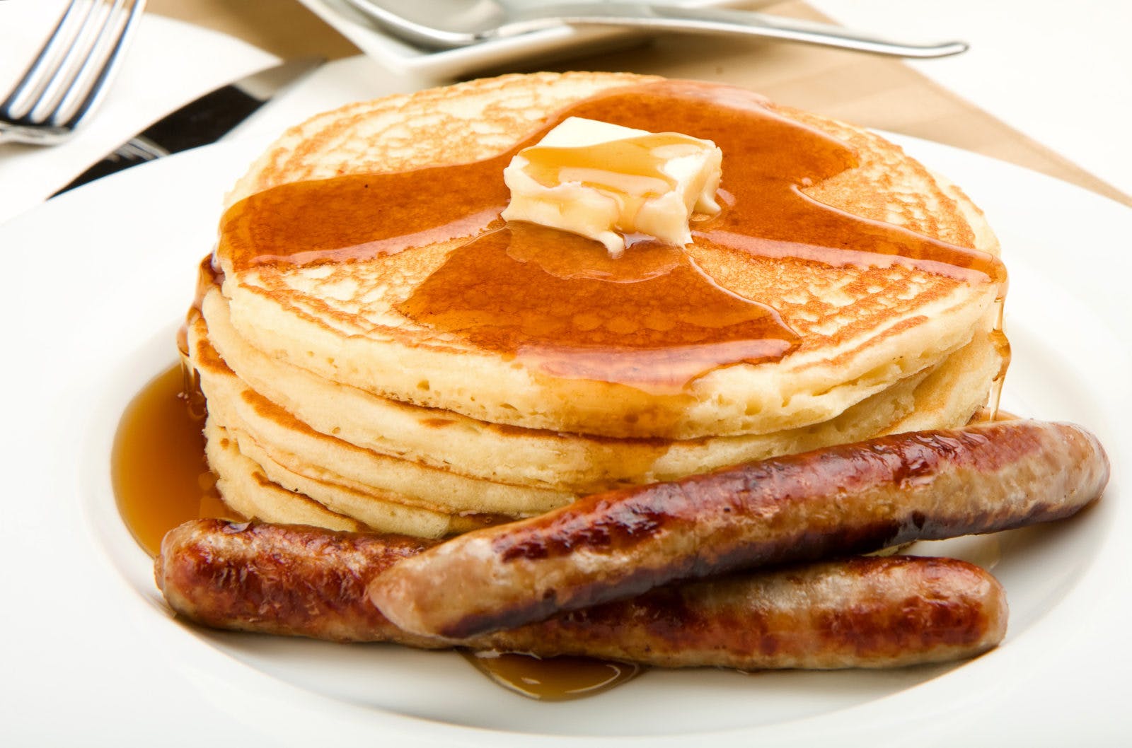 Breakfast of coffee pancakes and sausage with maple syrup